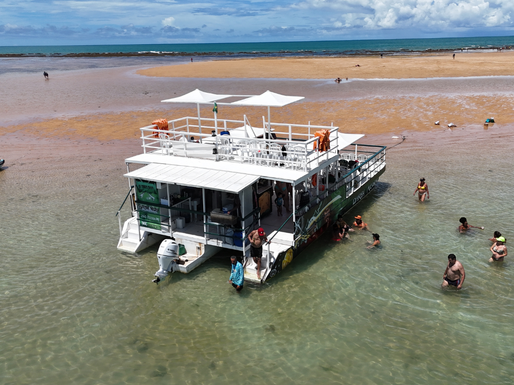 Barco da Paraíba Náuticos ancorado próximo à ilha com turistas desembarcando.