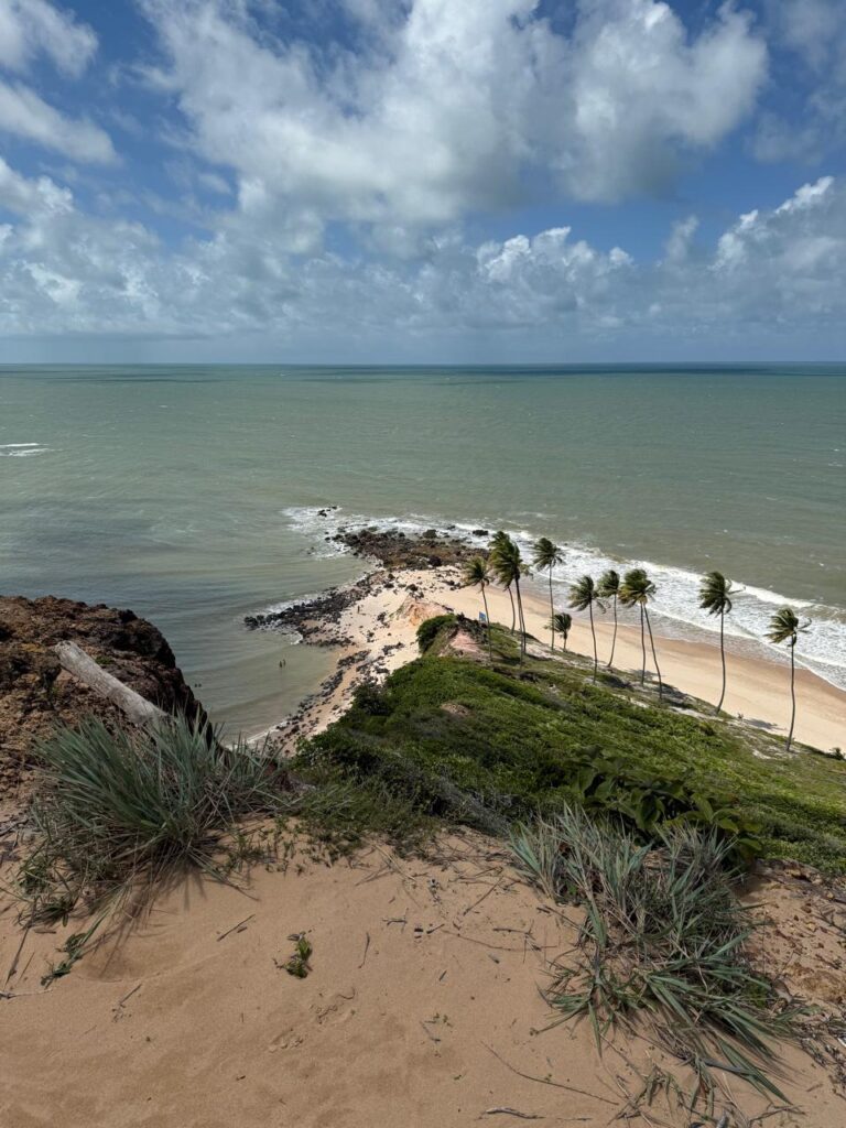 Mulher em pé em cima do quadriciclo com os braços abertos e o céu azul ao fundo.