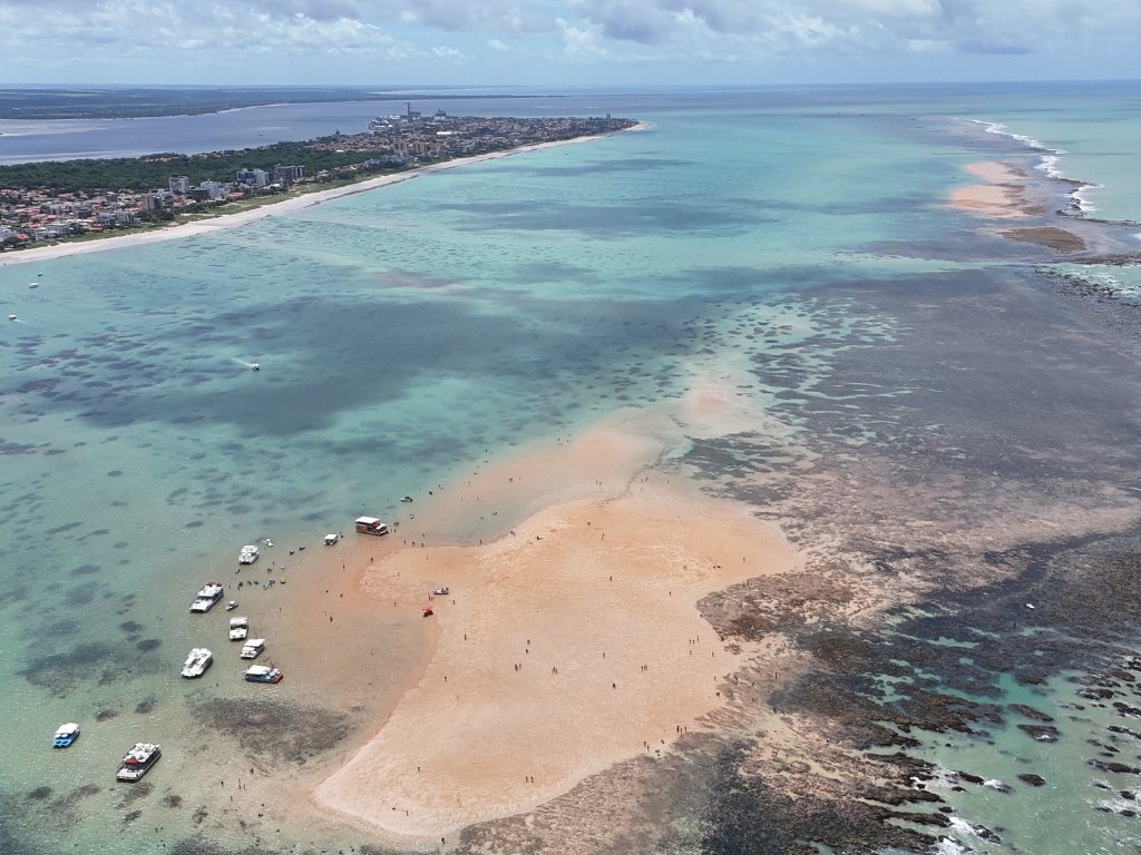 Turistas sentados em cadeiras de praia dentro da água rasa em Areia Vermelha.