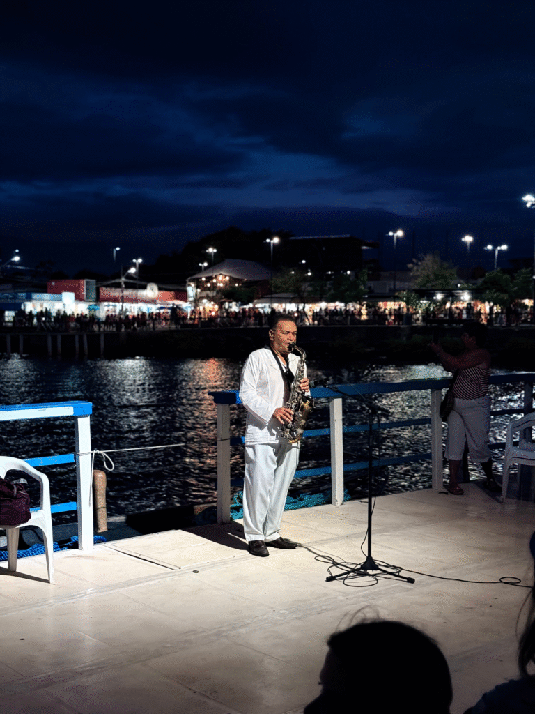 Violinista tocando a Ave Maria no convés do barco iluminado ao anoitecer.