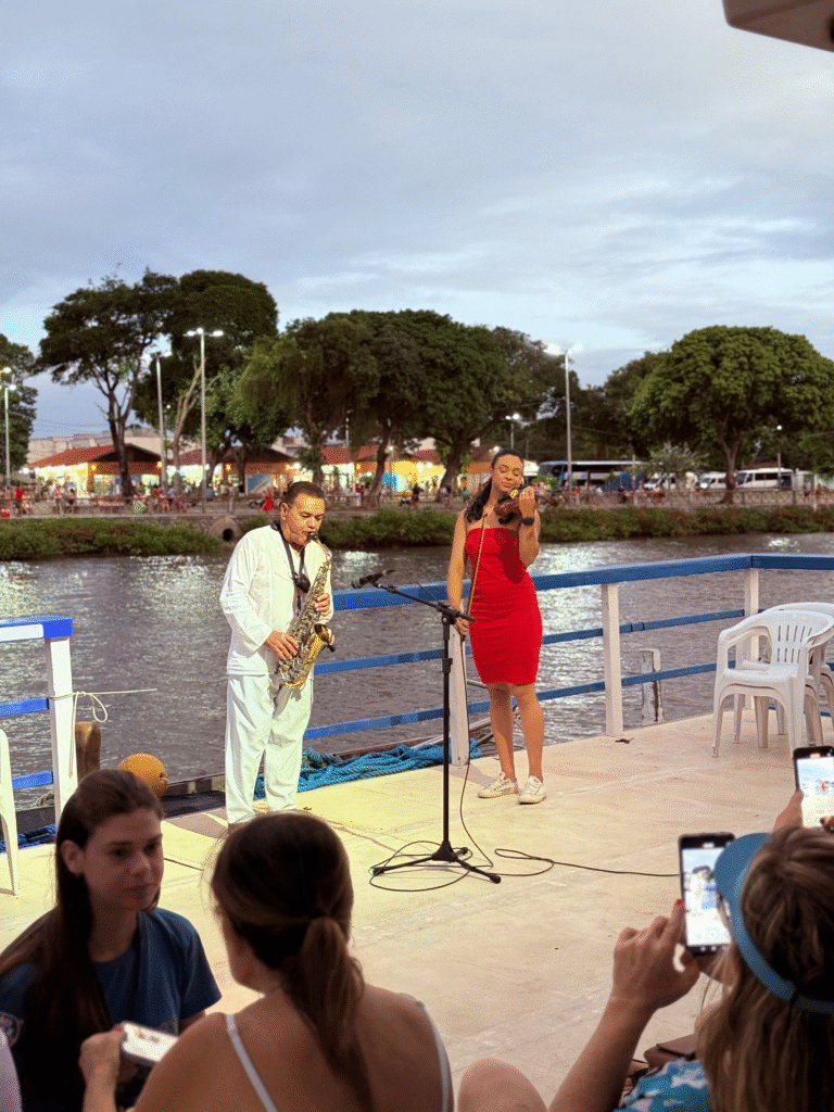Casal abraçado olhando o horizonte laranja do pôr do sol no barco