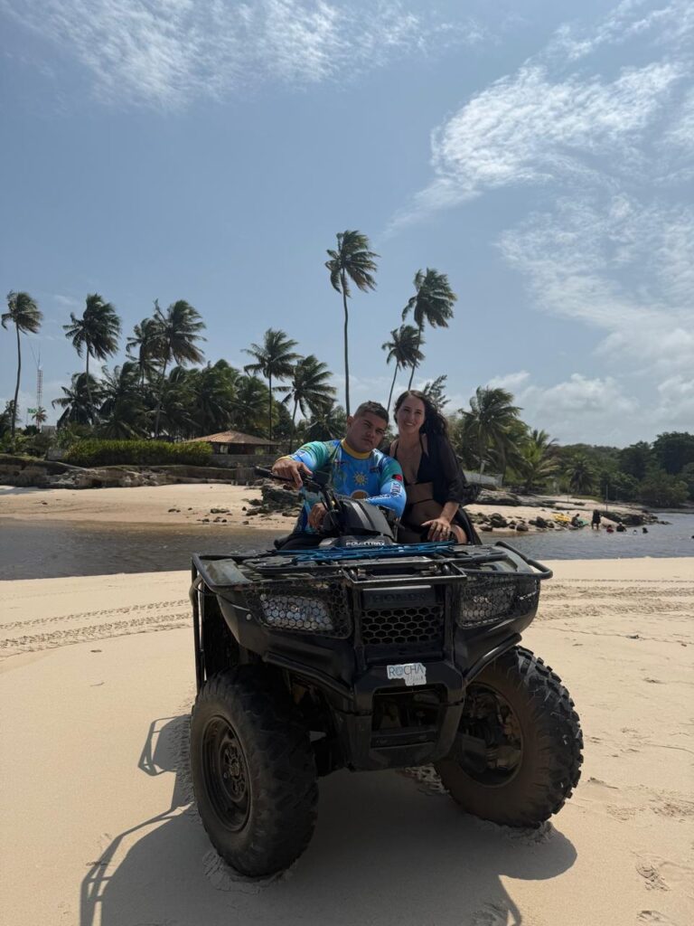 Turista pilotando quadriciclo em uma trilha de terra vermelha levantando poeira.
