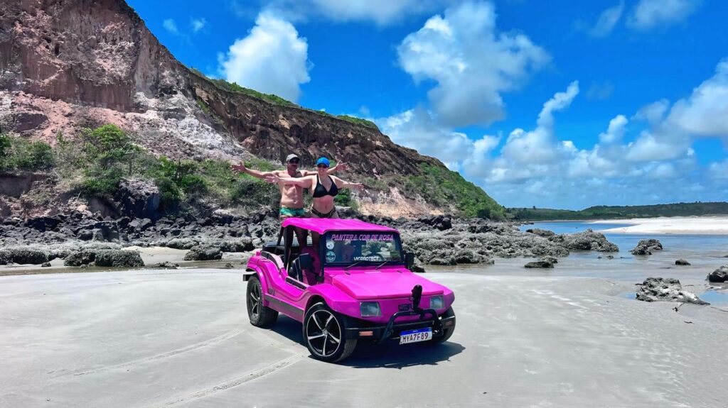 Buggy a acelerar numa estrada de terra cercada por coqueiros gigantes na Trilha dos Coqueirais.