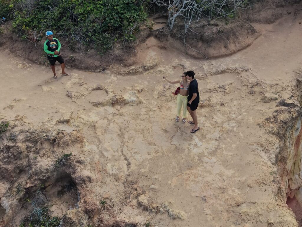 Casal usando capacetes de segurança sorrindo em cima do quadriciclo durante passeio no Litoral Sul.