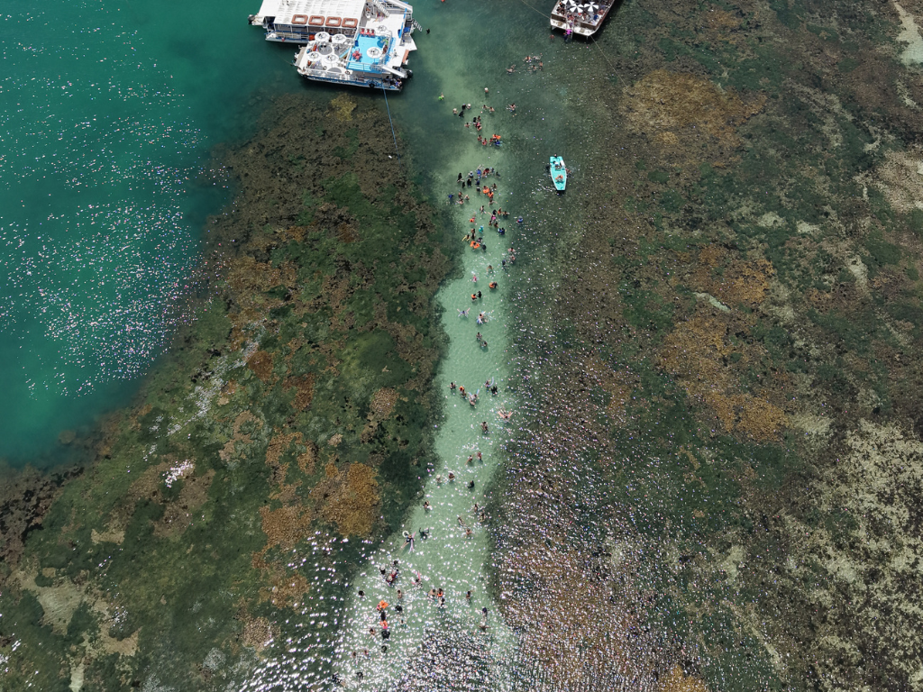 Vista aérea aproximada das águas verde-esmeralda cobrindo os recifes de corais preservados em Picãozinho na maré baixa.