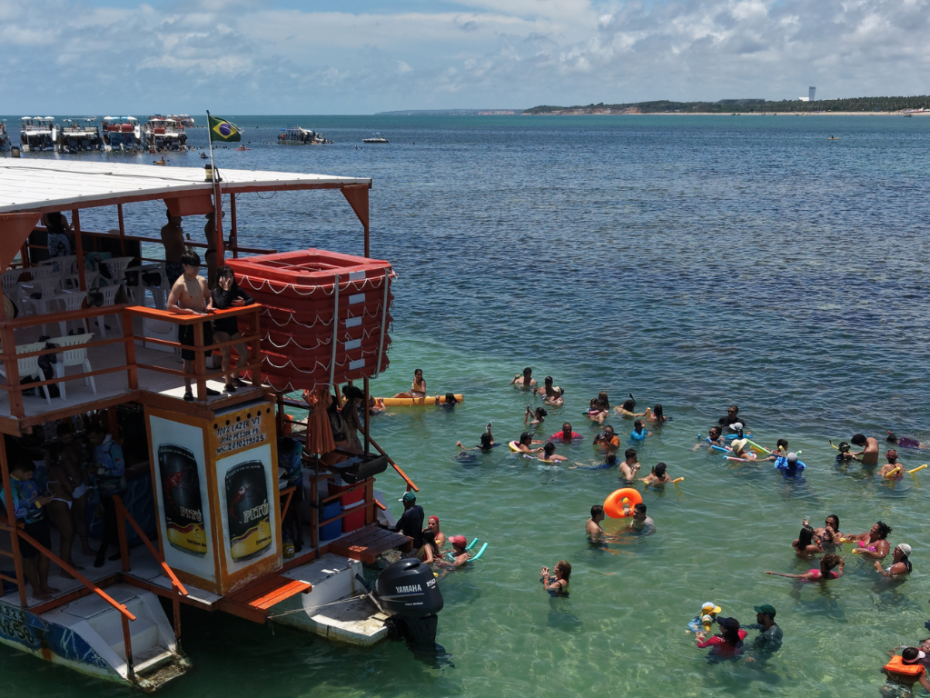 Criança fazendo mergulho com máscara rodeada de peixinhos coloridos nas águas rasas das Piscinas Naturais do Seixas.