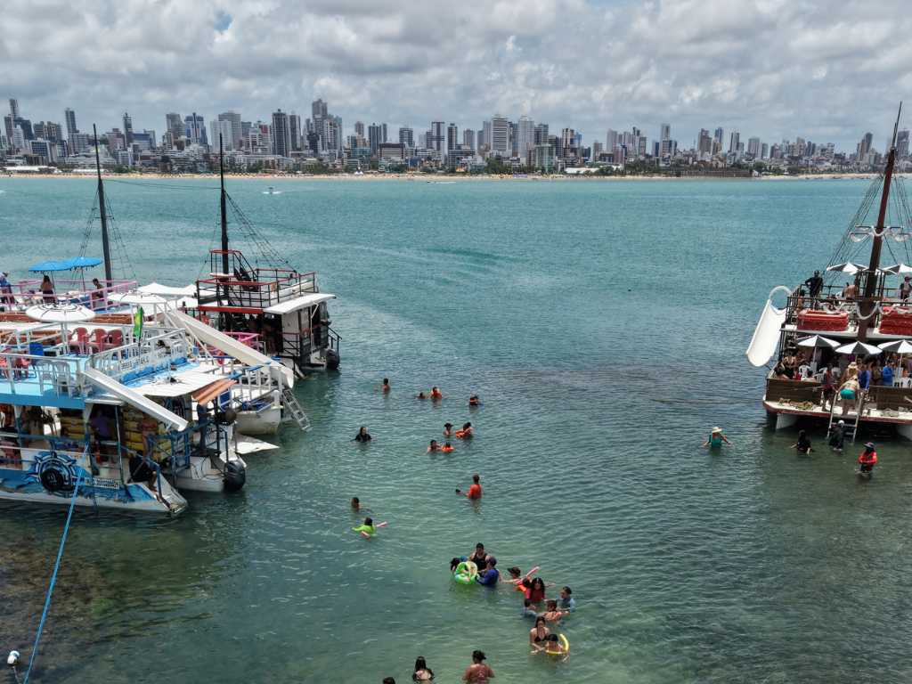 Estrutura do catamarã da Paraíba Náuticos ancorado nos corais de Picãozinho com toboágua e turistas aproveitando o sol.