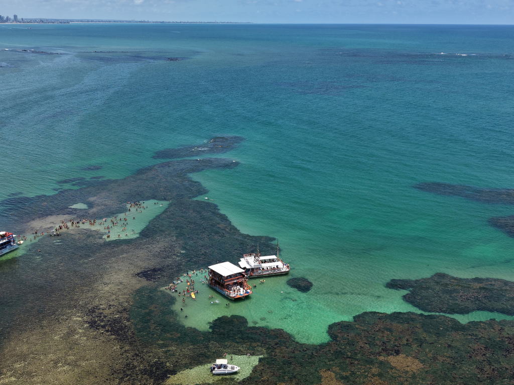 Turistas sorrindo e brindando nas férias de verão a bordo do barco da Paraíba Náuticos rumo às Piscinas do Seixas.