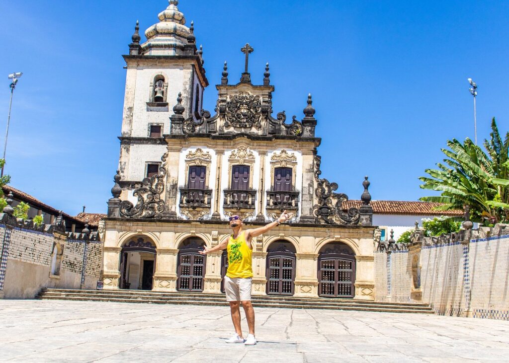 Turistas posando para foto no letreiro colorido "Eu Amo Jampa" na orla de Tambaú.