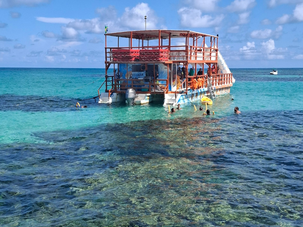Catamarã da Paraíba Náuticos chegando nas Piscinas Naturais do Seixas com mar azul turquesa.