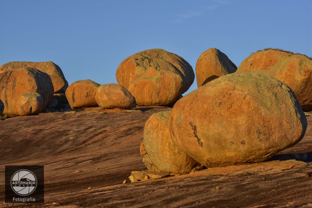 Silhueta de turistas em cima das pedras do Lajedo de Pai Mateus observando o pôr do sol dourado no Cariri.