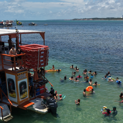 Criança fazendo mergulho com máscara rodeada de peixinhos coloridos nas águas rasas das Piscinas Naturais do Seixas.