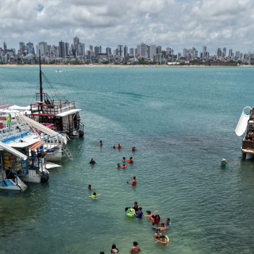 Estrutura do catamarã da Paraíba Náuticos ancorado nos corais de Picãozinho com toboágua e turistas aproveitando o sol.