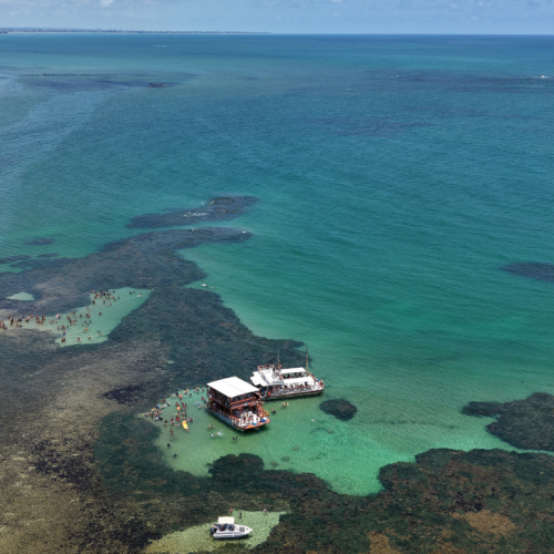 Turistas sorrindo e brindando nas férias de verão a bordo do barco da Paraíba Náuticos rumo às Piscinas do Seixas.