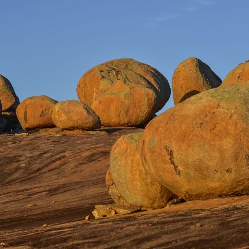 Silhueta de turistas em cima das pedras do Lajedo de Pai Mateus observando o pôr do sol dourado no Cariri.