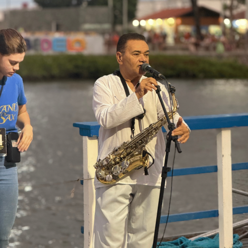 Taças de espumante sendo brindadas com o pôr do sol ao fundo no barco.