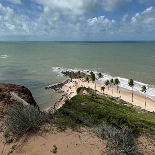 Mulher em pé em cima do quadriciclo com os braços abertos e o céu azul ao fundo.