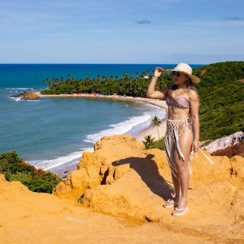 Turista em cima do quadriciclo apontando para a formação rochosa do Mirante Dedo de Deus.