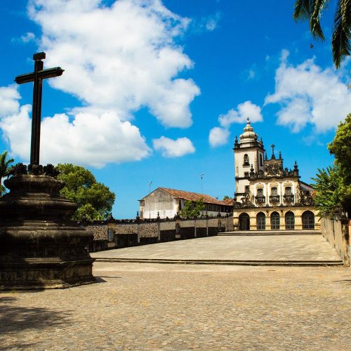 Fachada imponente do Centro Cultural São Francisco com o cruzeiro de pedra na frente.