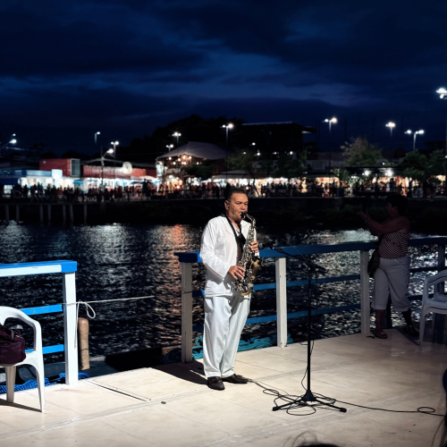 Violinista tocando a Ave Maria no convés do barco iluminado ao anoitecer.