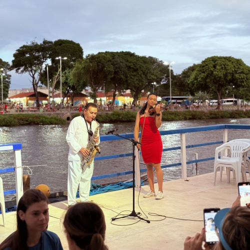 Casal abraçado olhando o horizonte laranja do pôr do sol no barco
